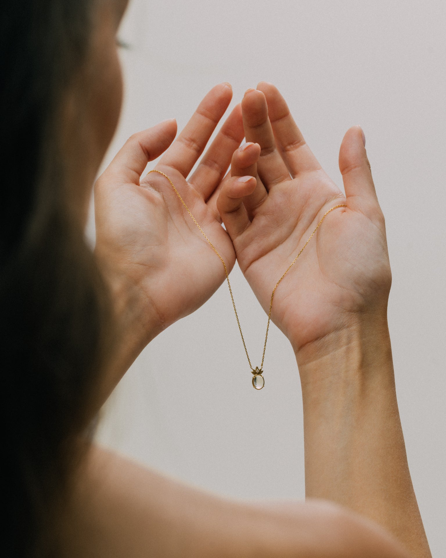 A woman holding the complete THALYRA necklace